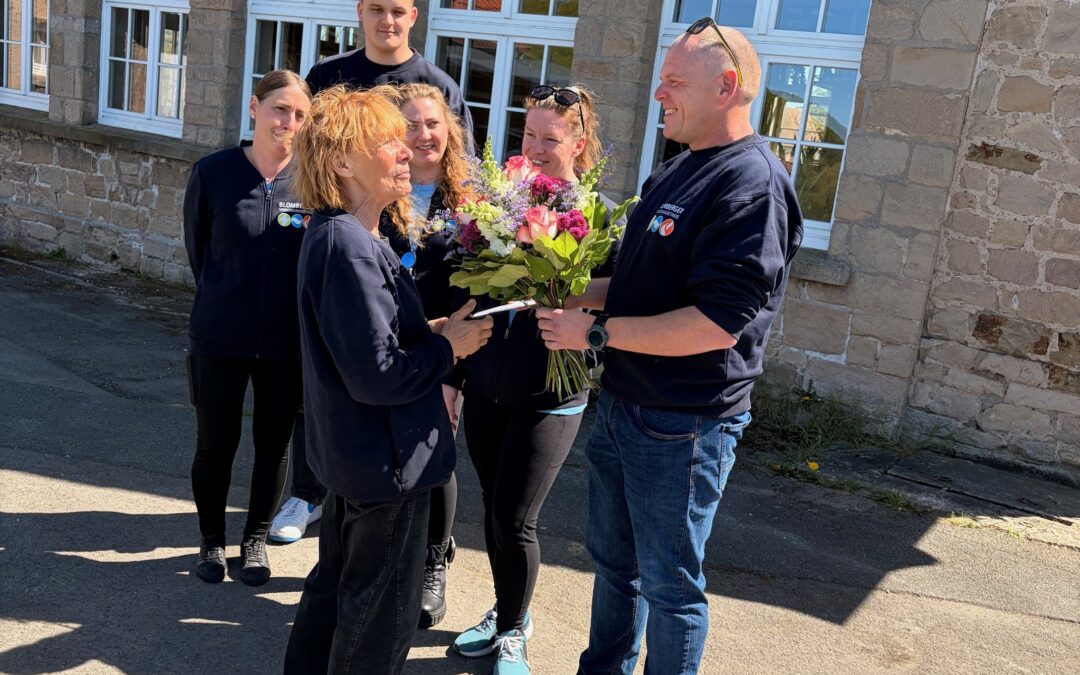 !B Der Jubilarin wird im Kollegenkreis ein Blumenstrauß überreicht